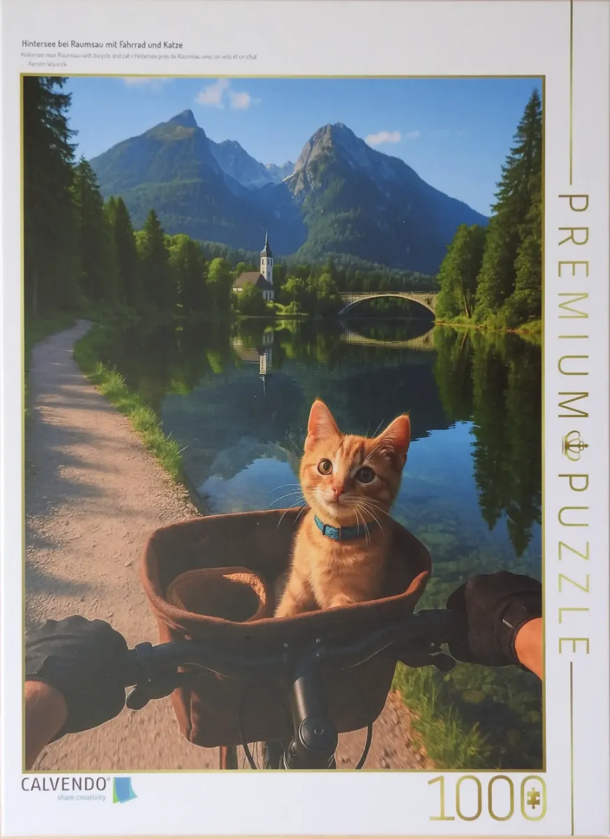 First-person view of an orange kitten in a bicycle basket, with a mountain lake and church in the background.