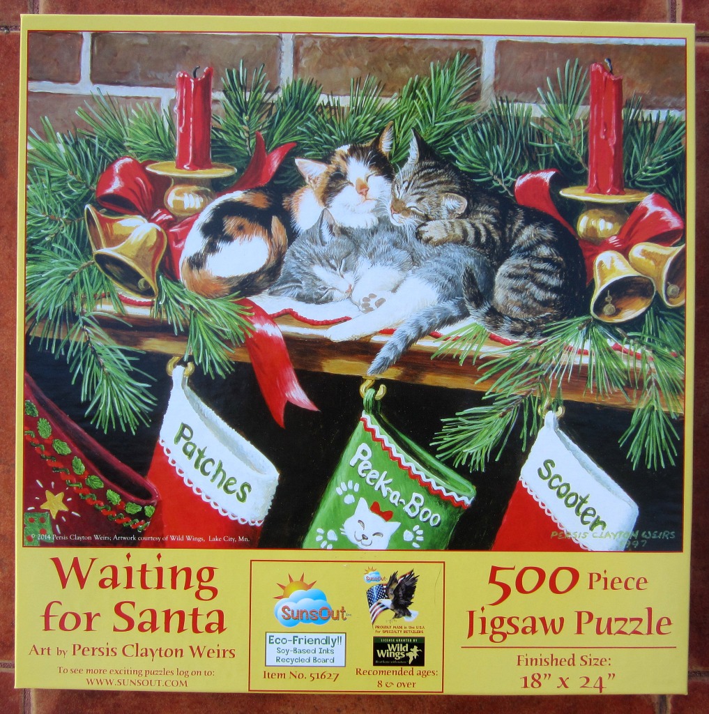 A painting of three kittens sleeping on a fireplace mantel decorated for Christmas with stockings, pine branches, and candles