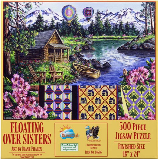 A log cabin by a mountain lake with two hot air balloons in the sky, framed by quilts in the foreground.