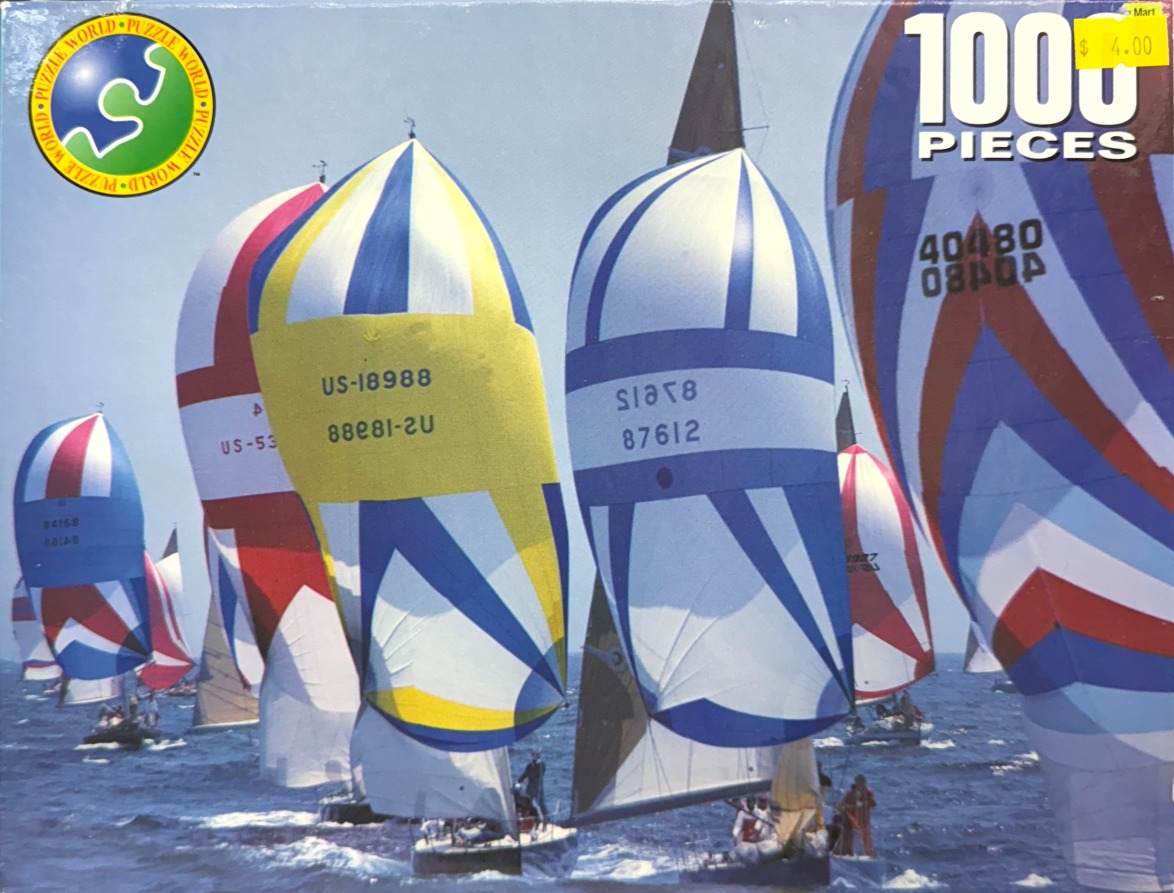 Multiple sailboats with colorful spinnaker sails racing on the open sea under a clear blue sky.