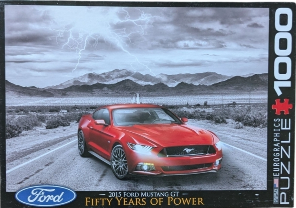 A red 2015 Ford Mustang GT parked on a desert road with lightning in the sky.