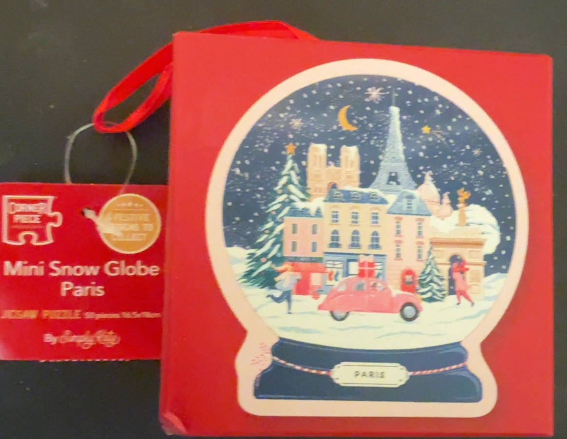 A snow globe illustration featuring famous Parisian landmarks against a dark blue, snowy night sky.