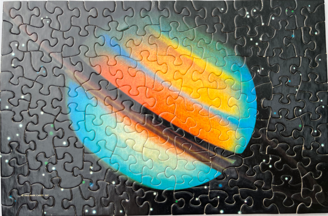 A colorful, stylized illustration of a planet with rings set against a dark, star-filled space background.