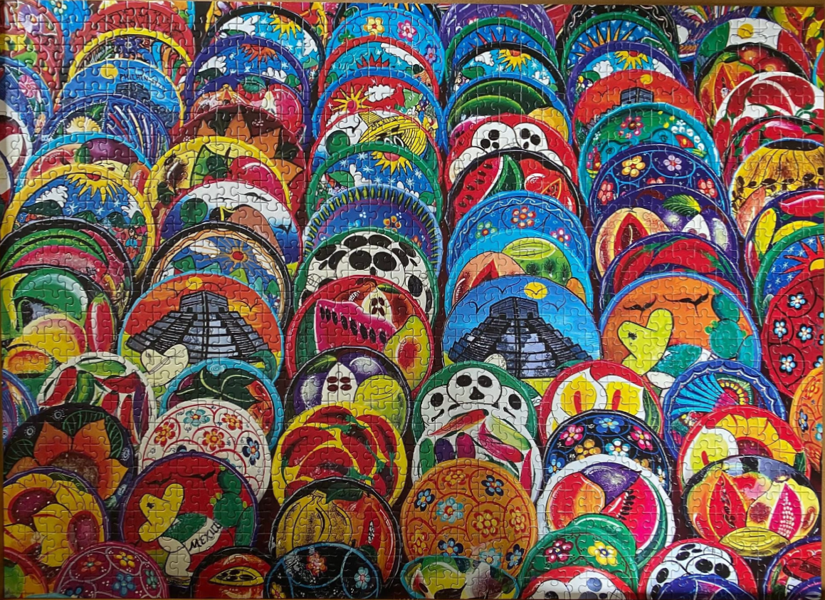 A vibrant collection of traditional Mexican hand-painted ceramic plates arranged in a dense, overlapping pattern.