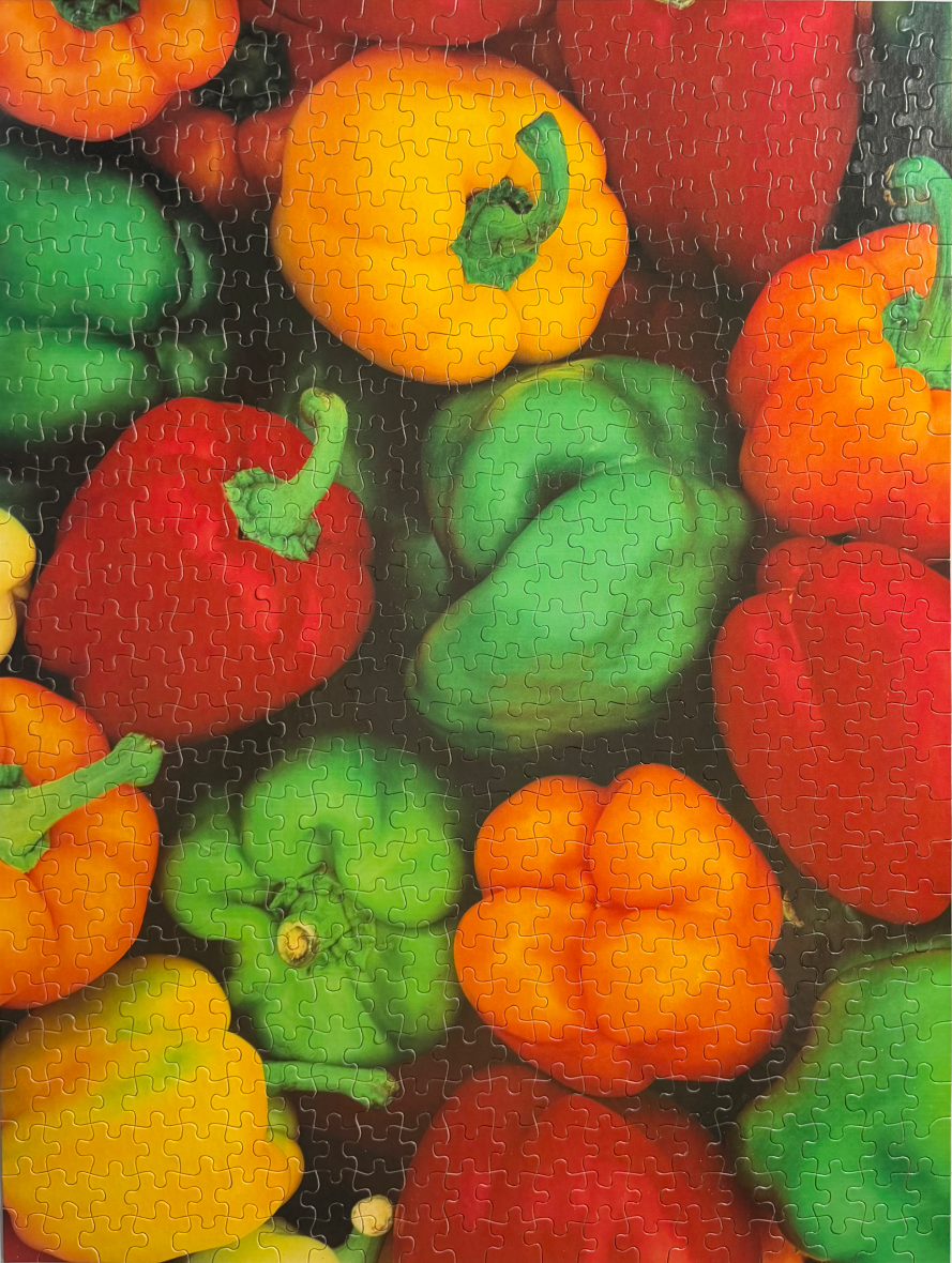 A vibrant, close-up photograph of assorted bell peppers in shades of red, yellow, orange, and green.