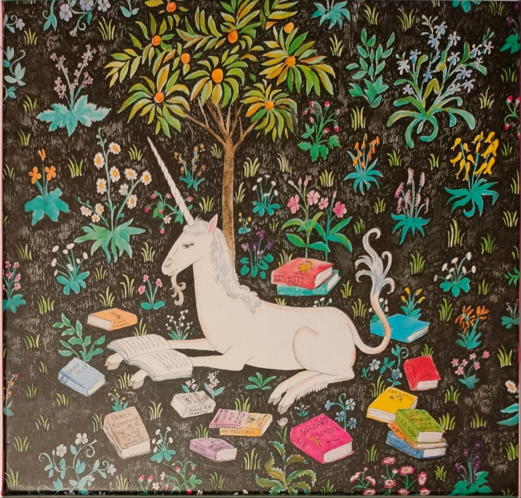 A white unicorn resting on a dark meadow surrounded by numerous fantasy books and wildflowers.