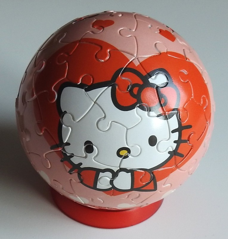 A spherical object featuring an illustration of Hello Kitty on a pink and red heart-patterned background.