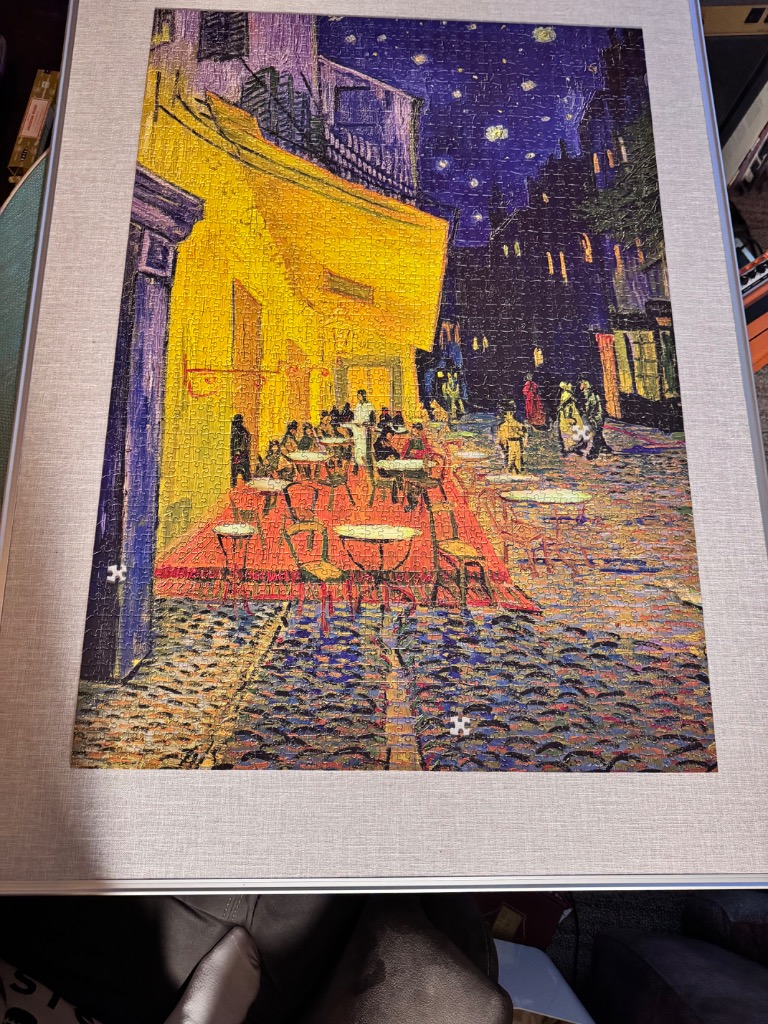 A reproduction of Van Gogh's Cafe Terrace at Night, featuring a bright yellow cafe against a dark, starry blue sky.