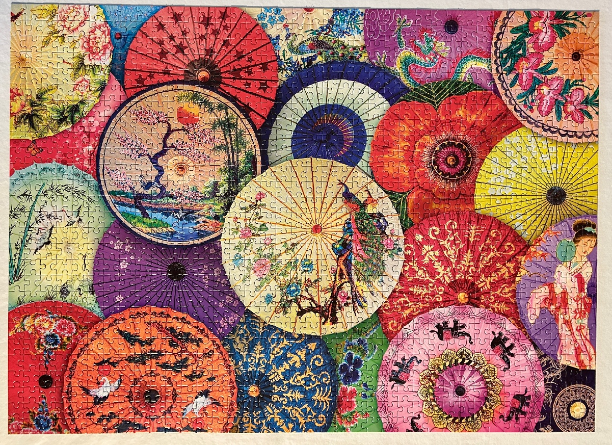 A dense, vibrant collection of overlapping traditional Asian paper umbrellas featuring floral, wildlife, and landscape motifs