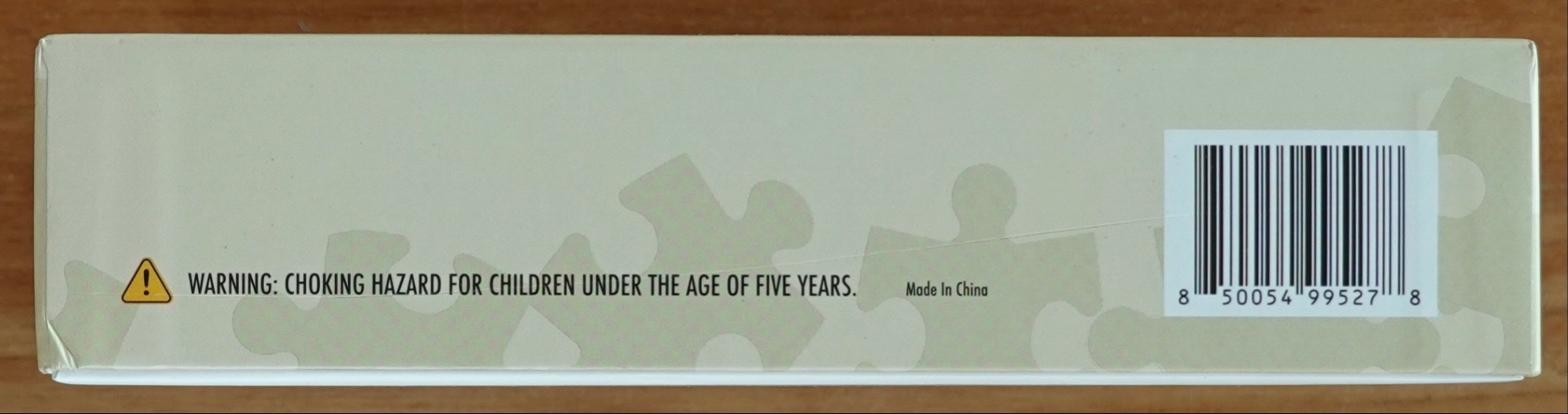 A light beige, rectangular surface with a faint puzzle piece pattern, a warning icon, and a barcode.