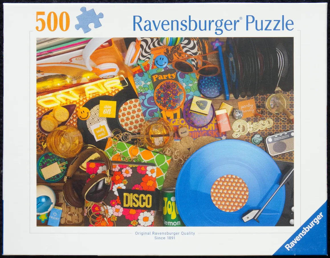 A cluttered tabletop scene featuring 1970s-style music and party memorabilia including a blue vinyl record and headphones.