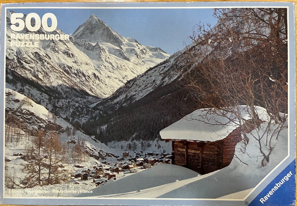 Snow-covered Swiss alpine village nestled in a mountain valley under a clear blue sky.