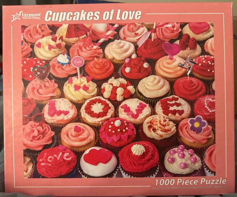 A collection of pink and red decorated cupcakes arranged closely together.