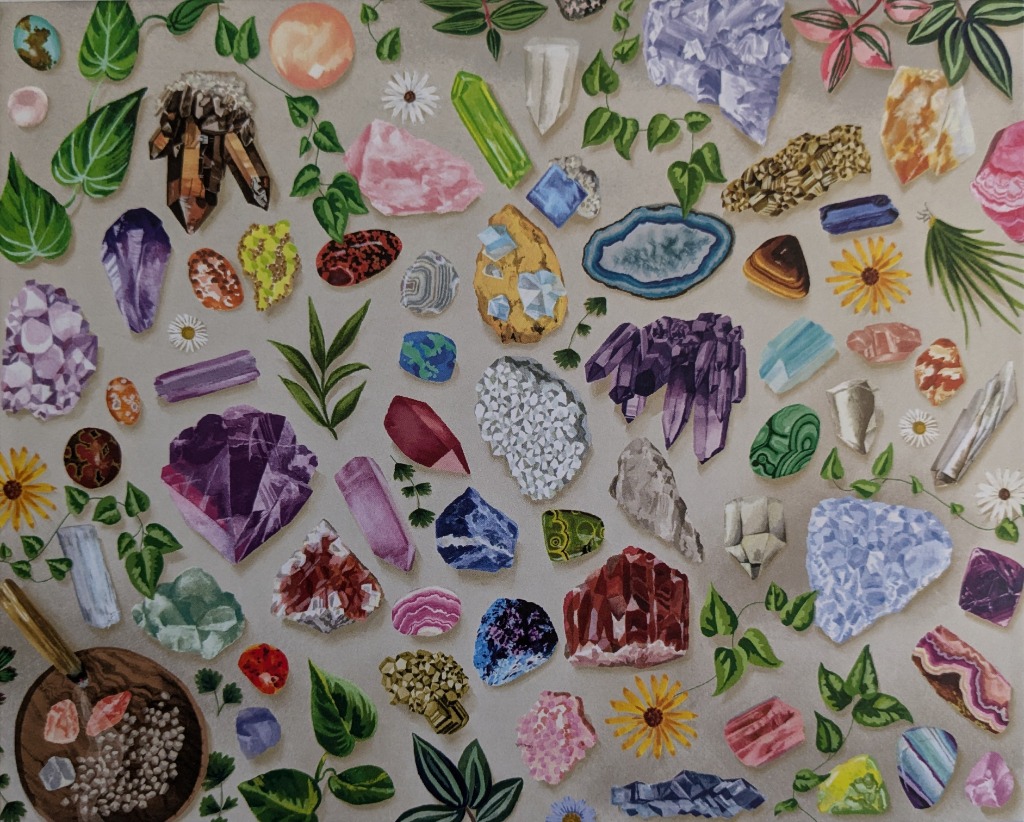 A collection of colorful crystals, minerals, and green leaves scattered across a light grey background.