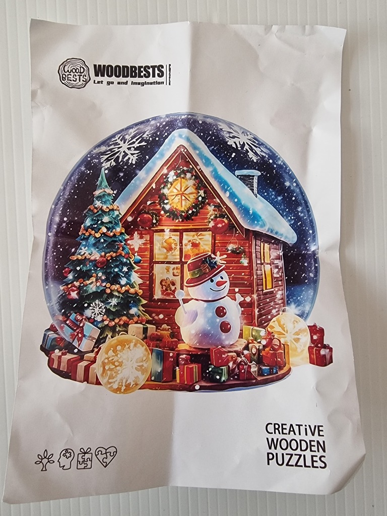 A snow globe scene featuring a cabin, a snowman, and a Christmas tree surrounded by presents.