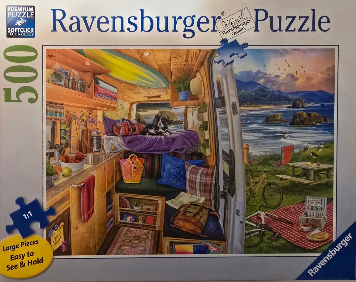 Interior of a cozy camper van parked overlooking a dramatic sunset coastal scene with a dog on the bed.