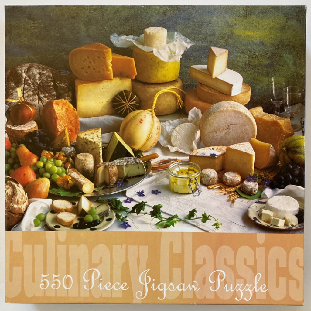 A detailed still-life photograph of a wide variety of cheeses, breads, fruits, and wine glasses on a rustic table.