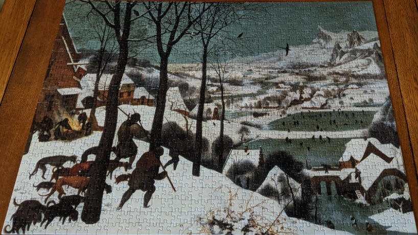 A classic painting of hunters returning through a snowy winter landscape with a village and frozen ponds below.