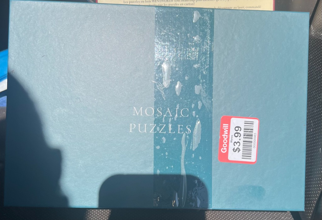 A teal rectangular surface with the text 'MOSAIC PUZZLES' printed in the center.
