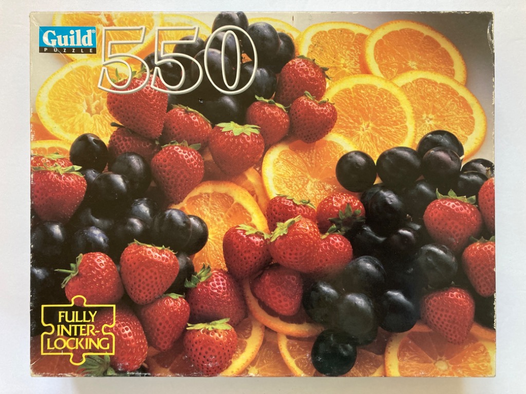 A close-up photograph of a vibrant, piled arrangement of fresh strawberries, dark purple grapes, and orange slices.