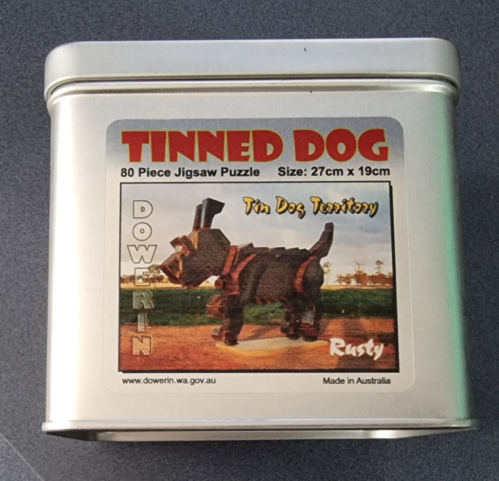 A photograph of a metallic sculpture of a dog standing in a field.