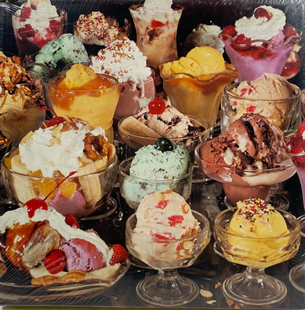 A collection of various ice cream sundaes and desserts in glass dishes against a black background.