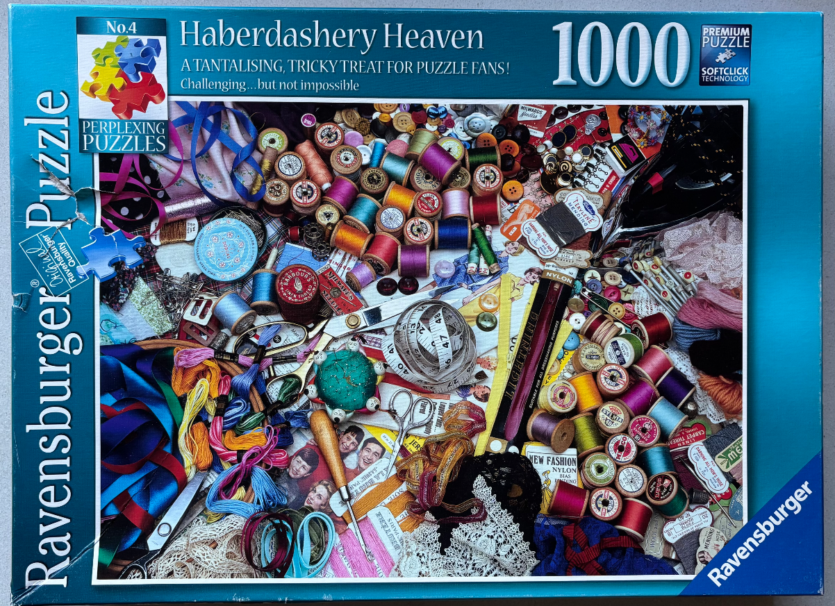 A cluttered tabletop overflowing with vintage haberdashery supplies like spools of thread, lace, ribbons, and scissors.