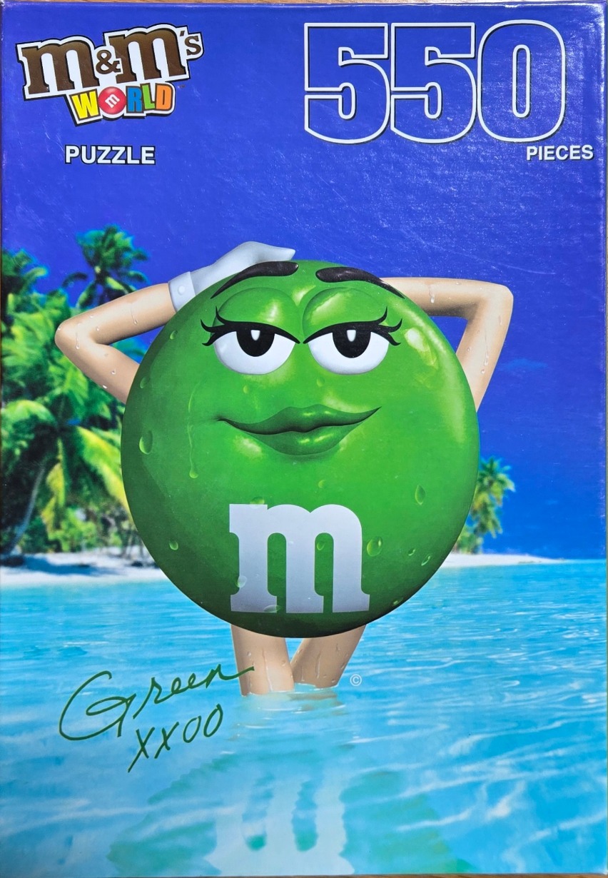 A cartoon green M&M character with eyelashes and white gloves posing in a tropical ocean setting.