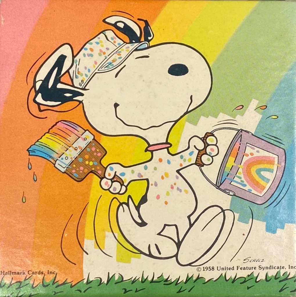 Snoopy character painting a rainbow over a bright, colorful background