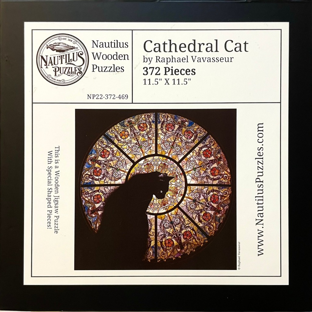 A silhouette of a black cat sitting in front of a circular, colorful stained glass window.