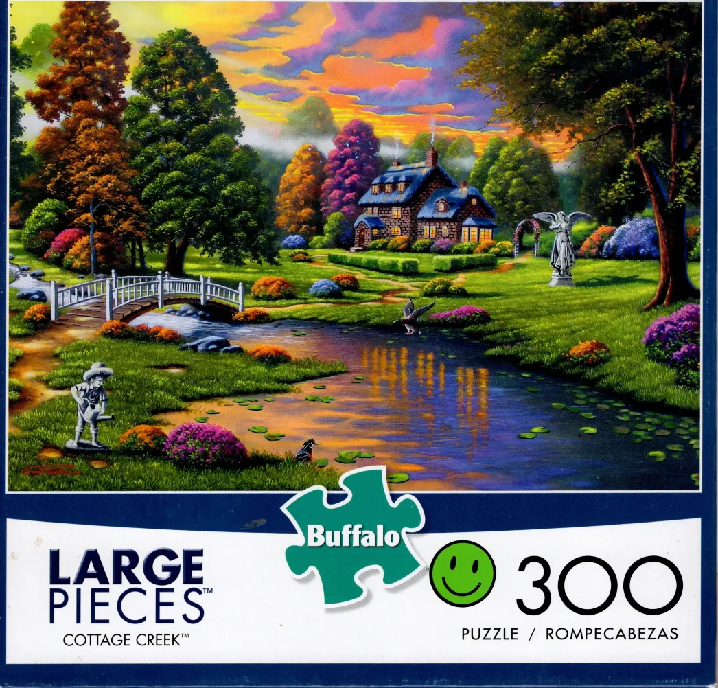 A peaceful cottage scene at sunset with a stream, stone bridge, and statue in a lush garden.