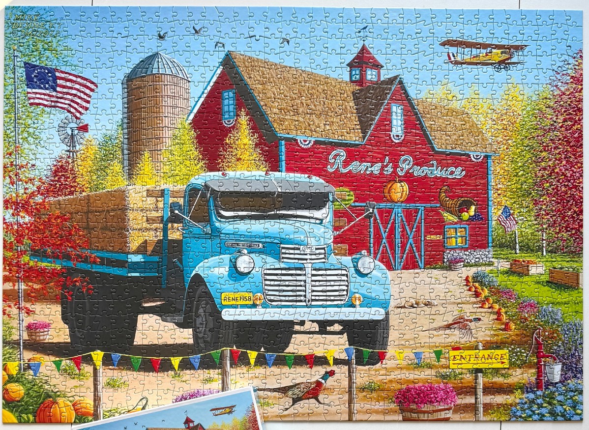 A vintage blue truck parked in front of a red barn labeled Rene
