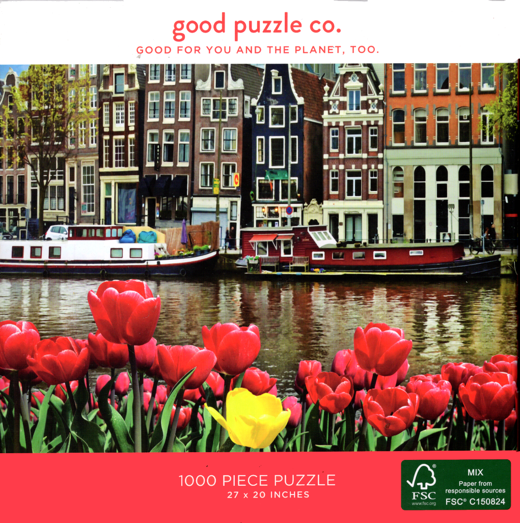 Vibrant red and yellow tulips in the foreground with Amsterdam canal houses and boats in the background