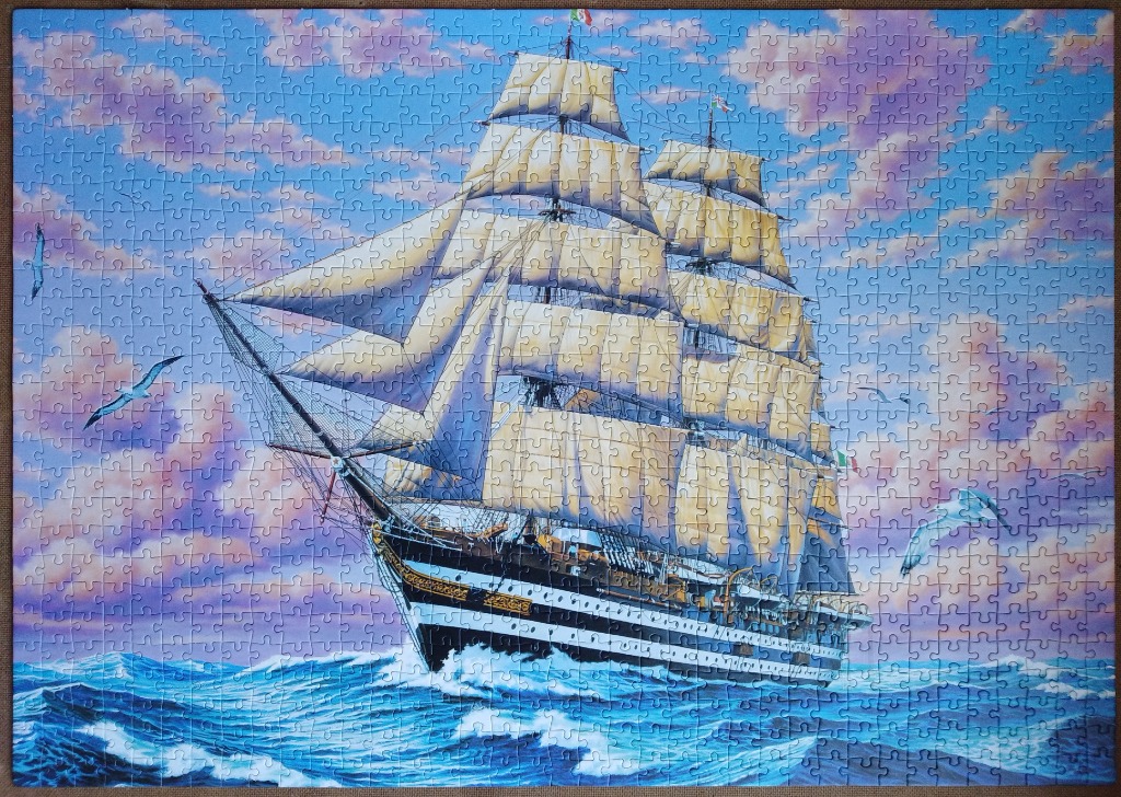 A tall ship sailing on rough ocean waters under a sunset sky.