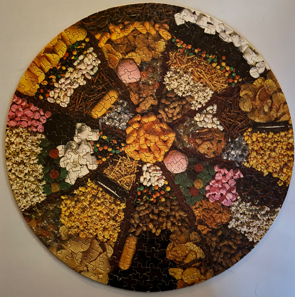 A circular photograph depicting a divided snack platter filled with various treats arranged in wedge-shaped segments.