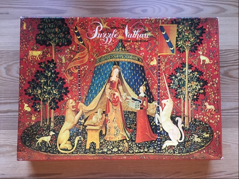 A reproduction of the Lady and the Unicorn tapestry showing a woman with a unicorn and lion under a blue tent.