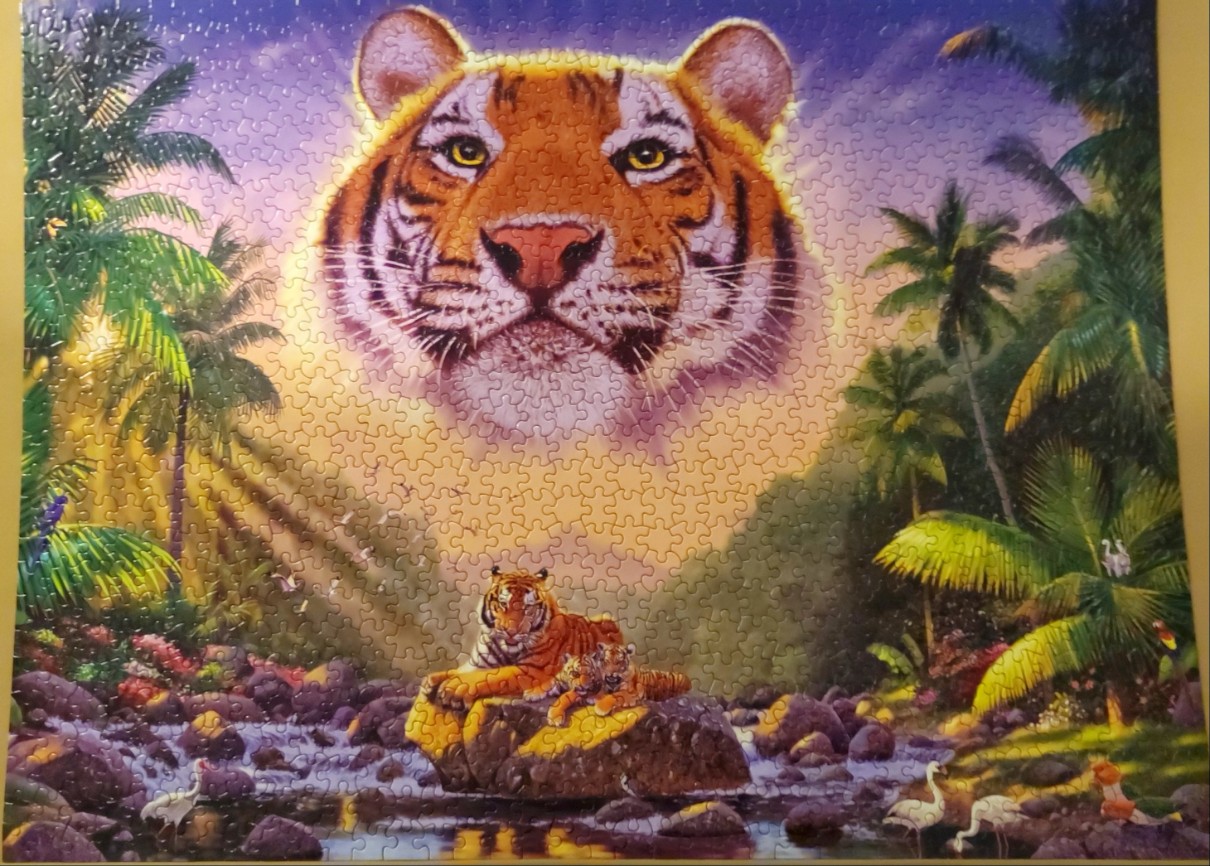 A fantasy illustration of a large spectral tiger face in the sky above a tiger mother and cub resting by a river.