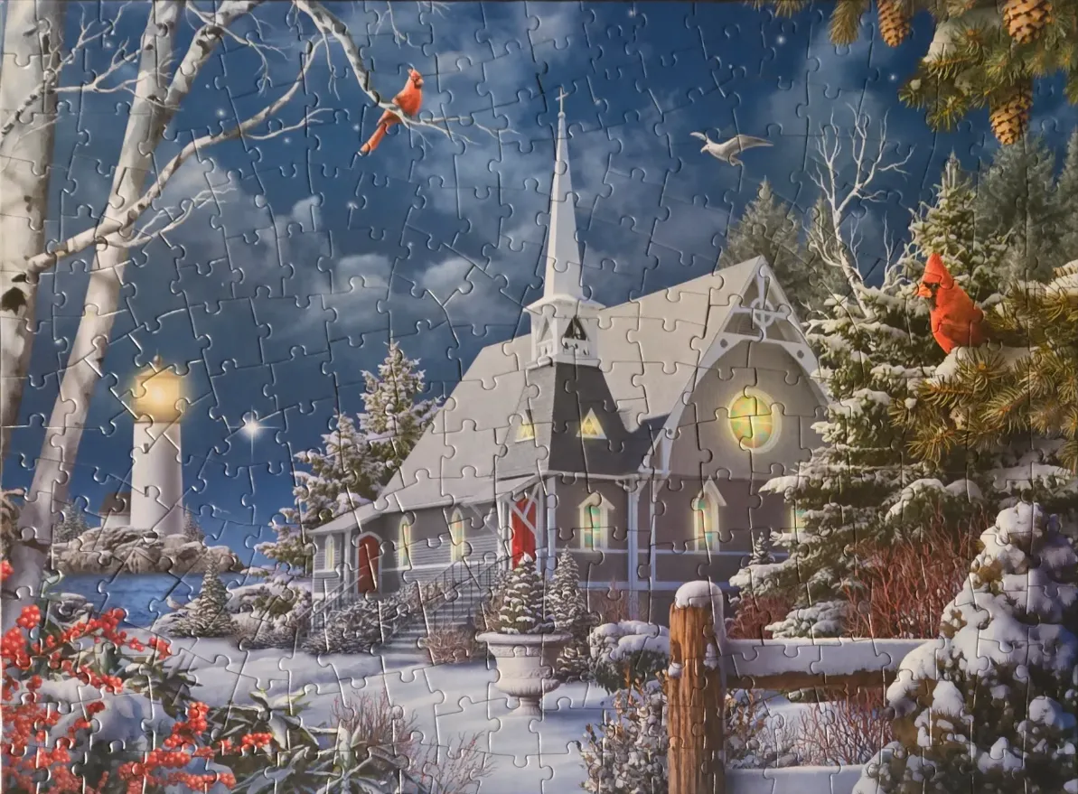 A snowy winter scene featuring a church, a lighthouse, and bright red cardinals.