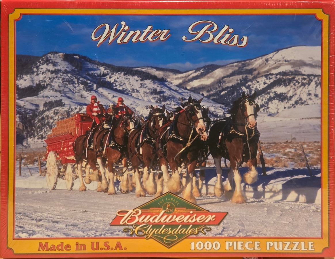 A team of Clydesdale horses pulling a red wagon through a snow-covered mountain landscape.