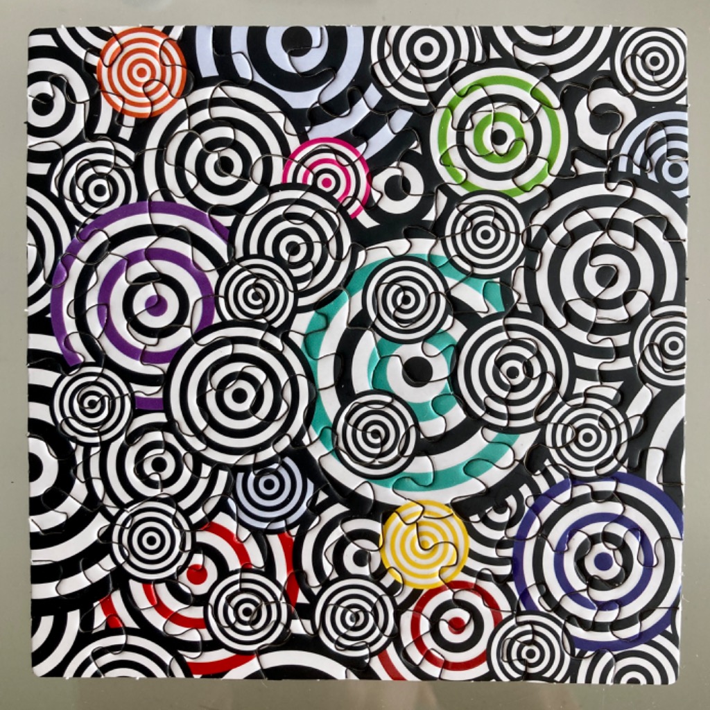 Abstract design of overlapping black and white circular bullseyes with pops of bright colors.