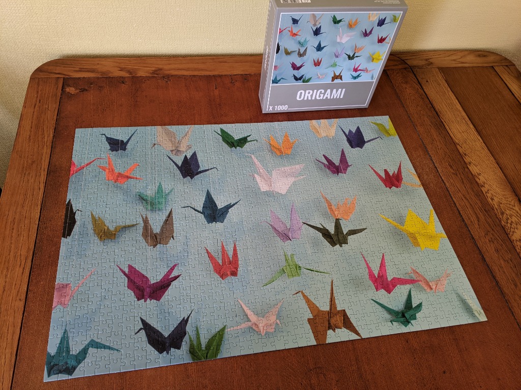 A collection of colorful paper origami cranes scattered across a pale blue background.