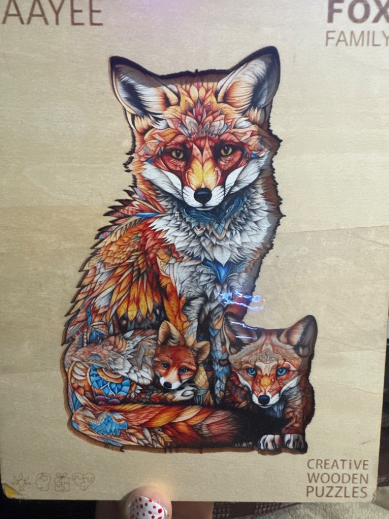 Illustration of a mother fox and two kits with intricate, ornate patterns set against a light wood background.