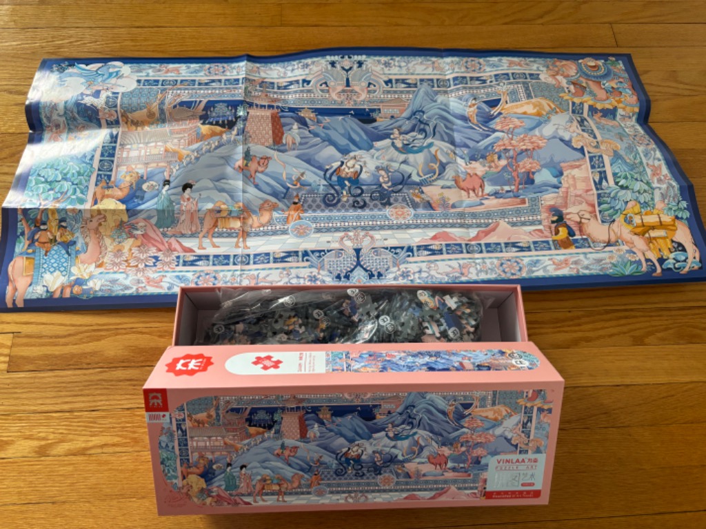 A panoramic illustration depicting an ancient Silk Road scene with camels, figures, and mountains in blue and coral tones.