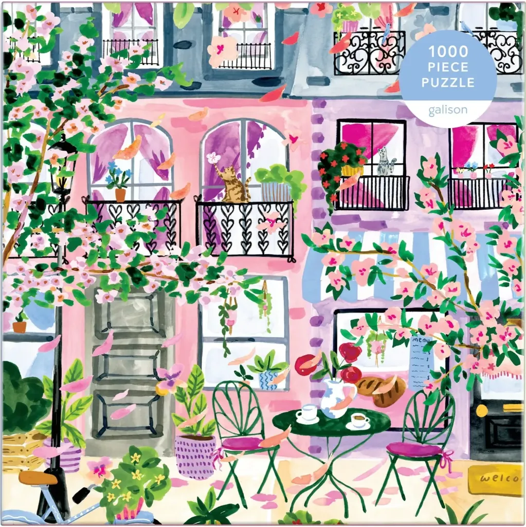 Illustration of a Parisian-style street corner with a café terrace, pink buildings, flowering trees, and a cat on a balcony