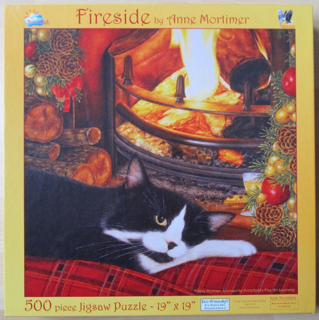 A black and white cat resting on a plaid blanket in front of a warm fireplace decorated for the holidays.