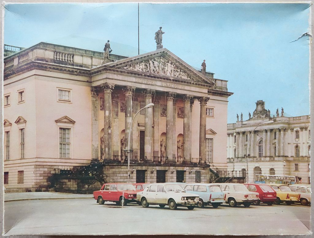 The historic Deutsche Staatsoper opera house in Berlin with vintage cars parked in the foreground.