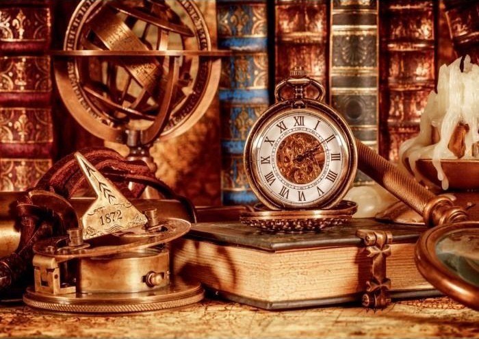 Vintage desk arrangement with an antique pocket watch, armillary sphere, and old books.