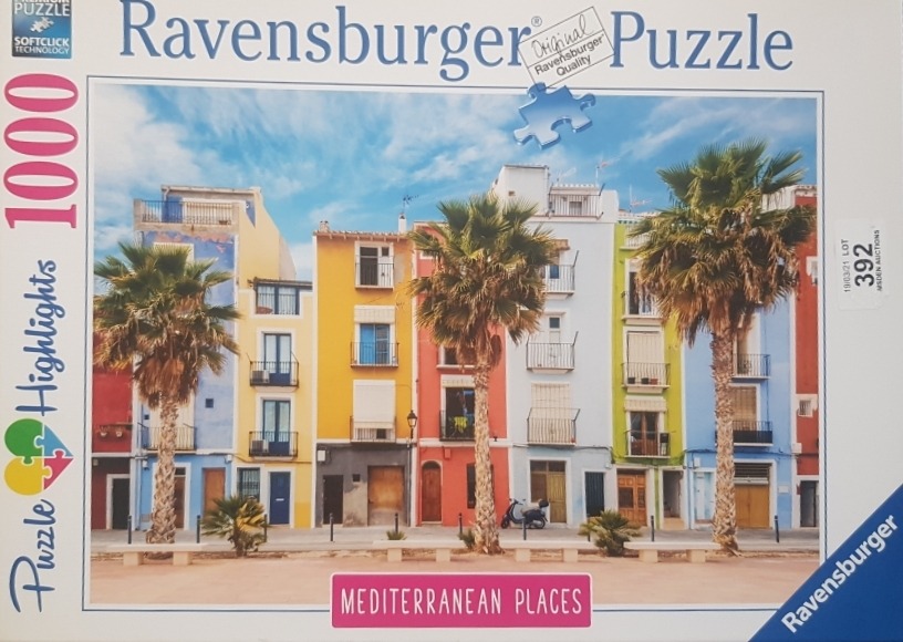 A row of brightly colored Mediterranean buildings behind tall palm trees against a blue sky.