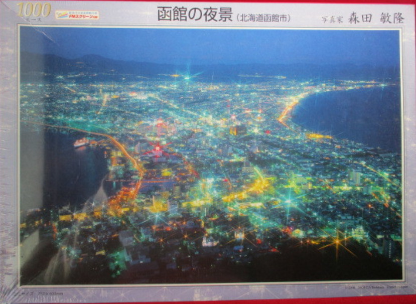 A panoramic night-time aerial photograph of the Hakodate city lights in Japan.
