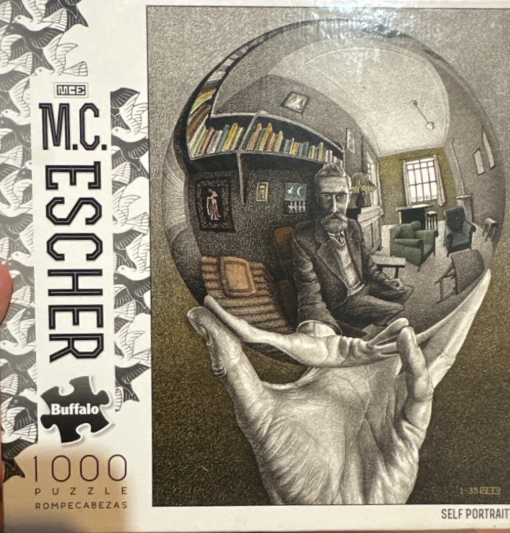 Hand holding a reflective sphere containing a self-portrait within an interior room.